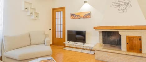 Ein Wohnzimmer mit Sofa, Fernseher, Kamin und einer Wand mit einem Zitat.