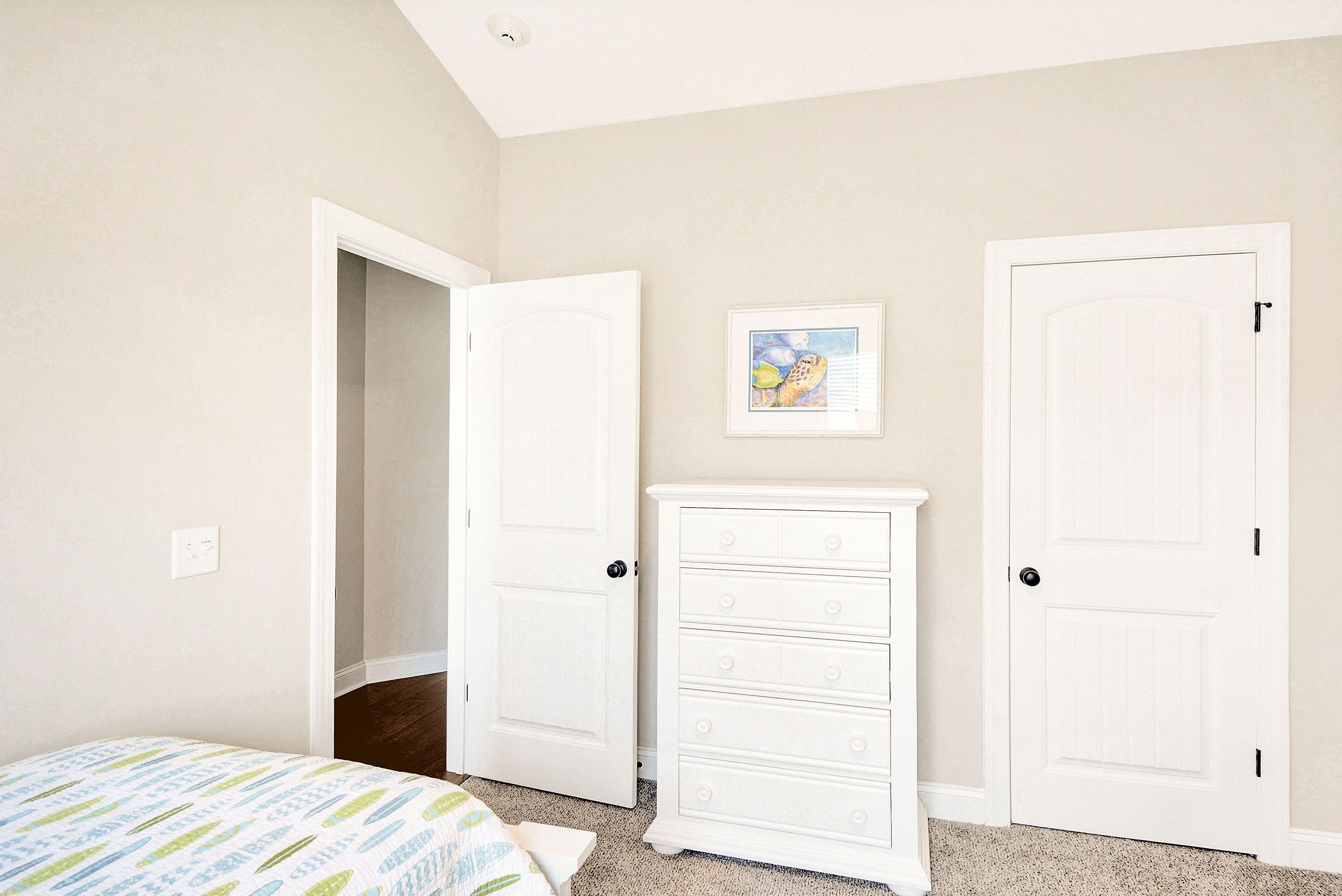 Une chambre à coucher avec un lit, une commode et deux portes fermées.
