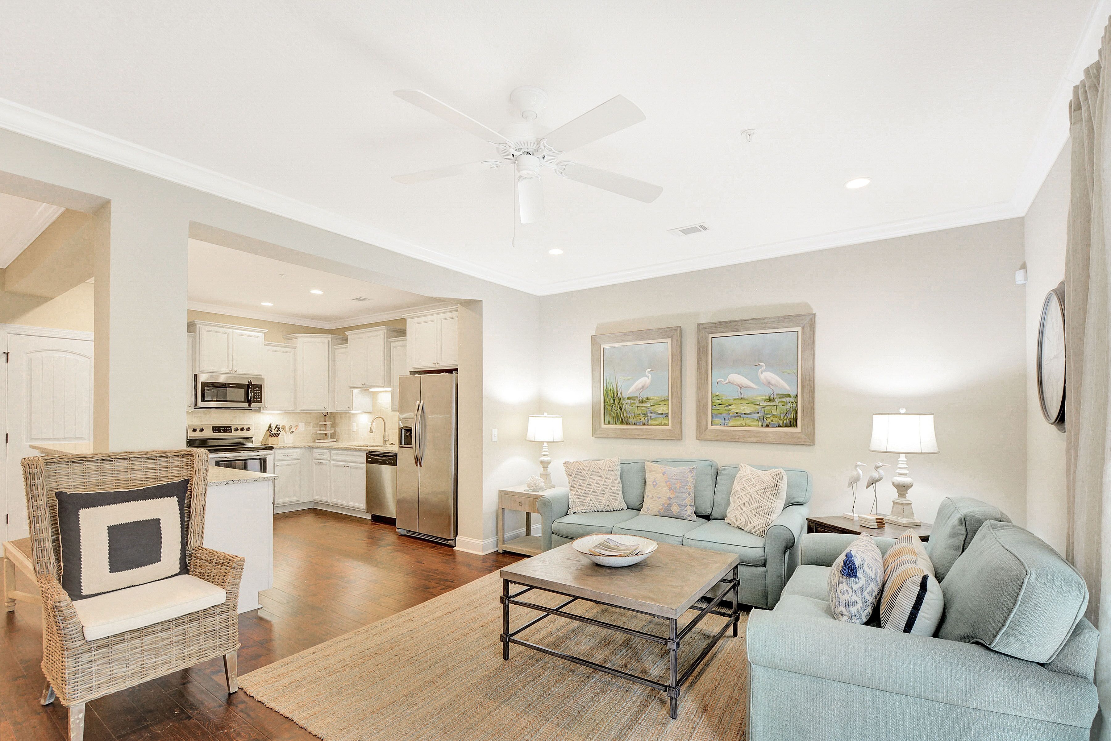 A spacious living area with a sofa, coffee table, and a dining table. There is a kitchen in the background with modern appliances.