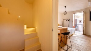Eine Treppe führt zu einem Schlafzimmer mit einem Bett, einem Schreibtisch und einer Hängelampe.