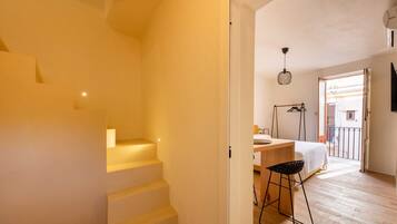 Eine Treppe führt zu einem Schlafzimmer mit einem Bett, einem Schreibtisch und einer Hängelampe.