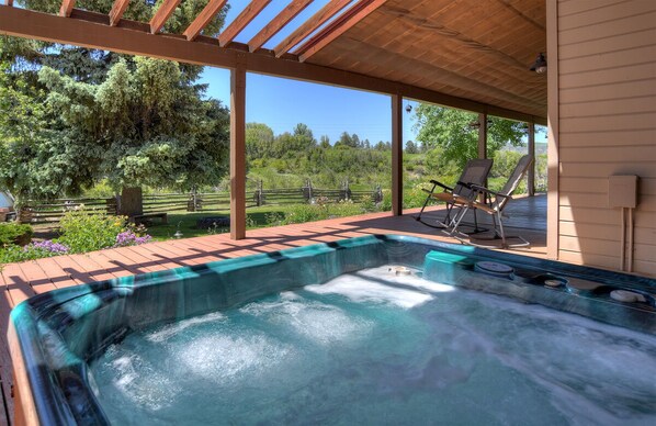 Relax in a serene hot tub surrounded by lush greenery and comfortable lounge chairs.