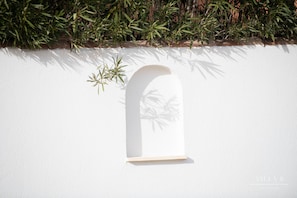 A white wall with a window and a shadow of a plant. - Villa B (Salernes)