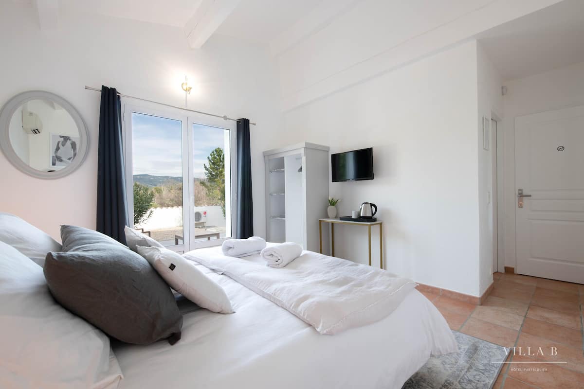 Camera d'albergo con letto, televisore, armadio e vista sull'esterno.