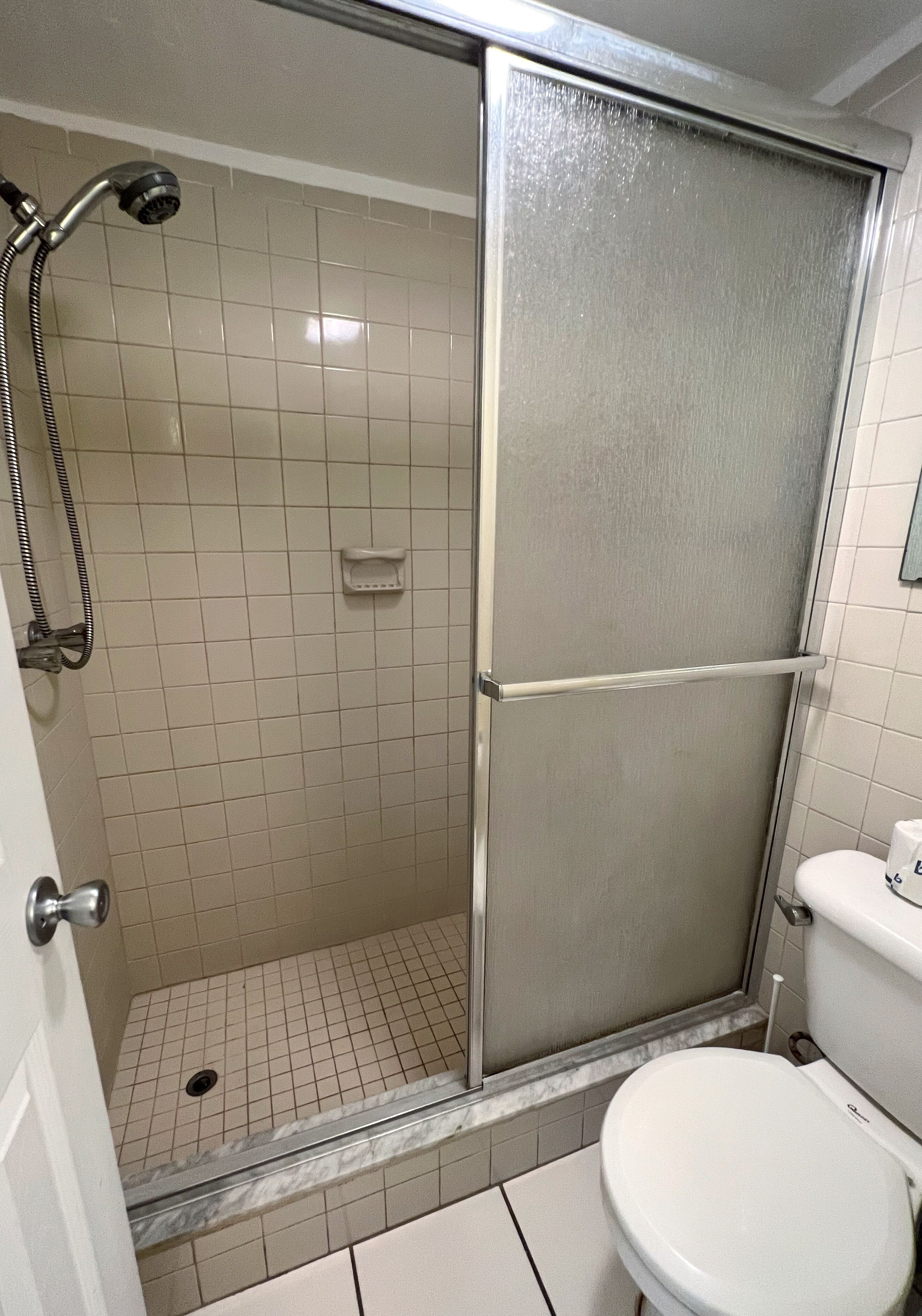 Un baño con cabina de ducha, inodoro y lavamanos.