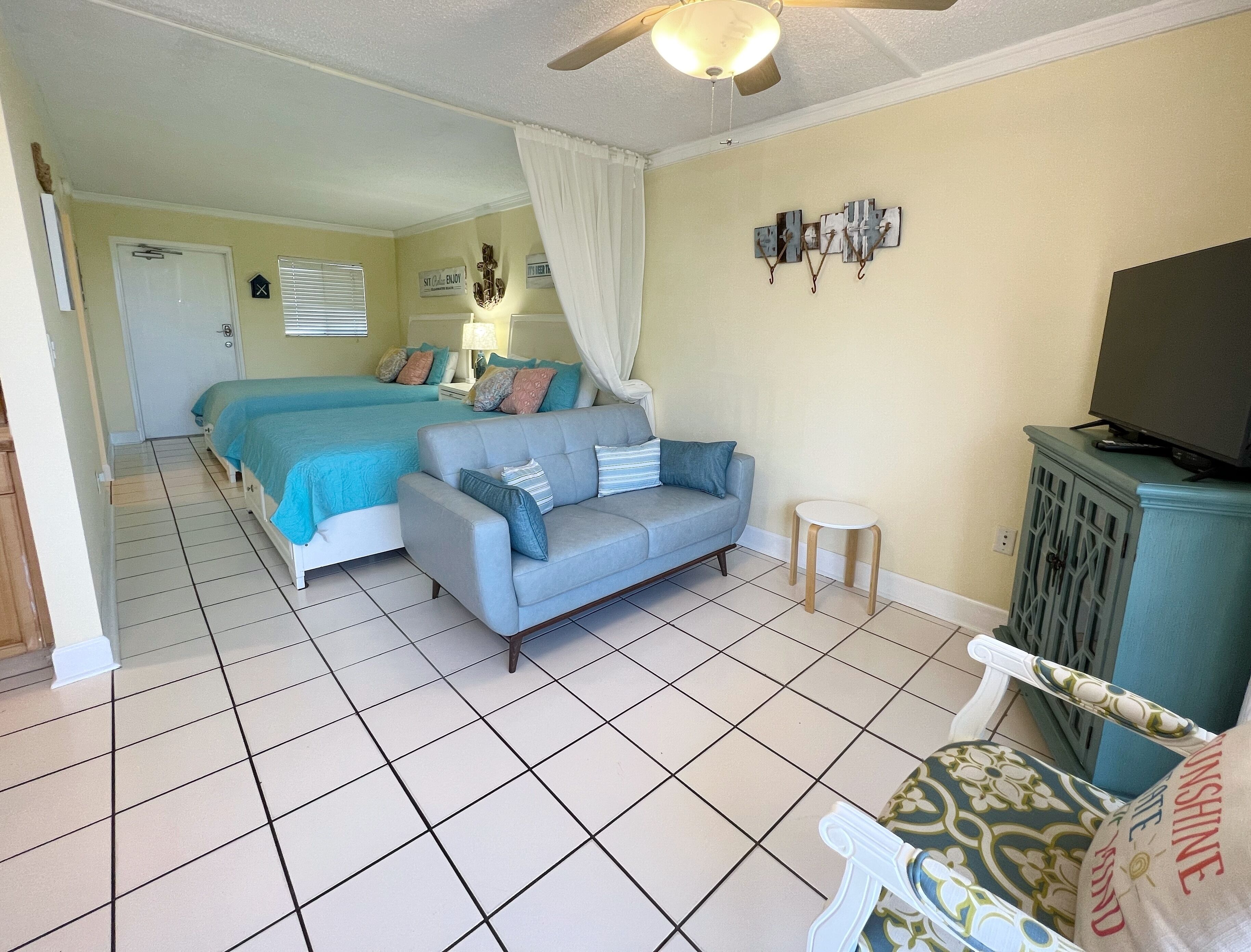 Een slaapkamer met een bed, een bank, een televisie en een bijzettafeltje.