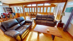 A cozy living room with two leather sofas, a wooden coffee table, and a bookshelf. - 3 bedroom, 1 bath elevated home with private pool, walking distance to beach! (Isle of Palms)