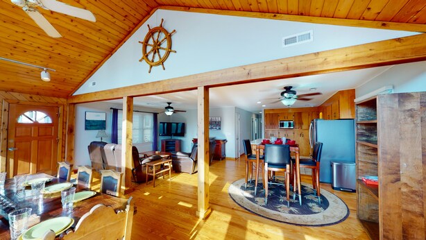 A spacious living area with wooden floors, a dining table set for six, and a kitchen with wooden cabinets and appliances. - 3 bedroom, 1 bath elevated home with private pool, walking distance to beach! (Isle of Palms)