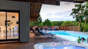 Terraza exterior con jacuzzi, sillas de descanso y piscina.
