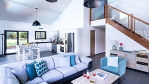 Un espacio moderno para vivir con cocina, comedor y una escalera que lleva a un nivel superior.