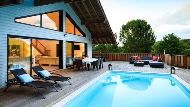 Una casa moderna con piscina, mobiliario exterior y zona de comedor.