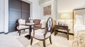 A hotel room with a bed, a desk with a lamp, a chair, a sofa, and a decorative wall piece. - SuperHost - Deluxe Studio with Stunning Marina Views - JW Marriott Dubai Marina (Dubai)