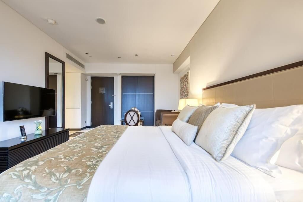A hotel room with a large bed, a flat-screen TV, a desk, and a chair.