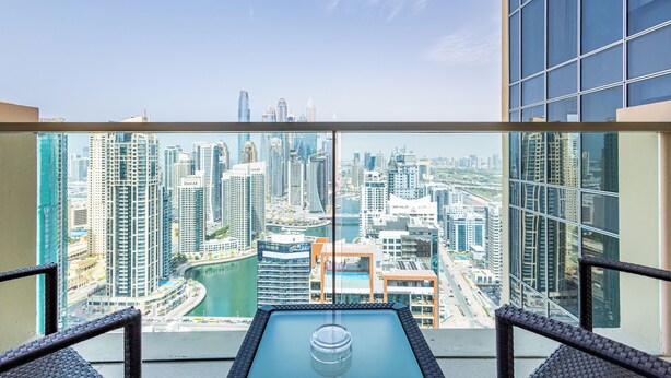 A high-rise hotel room with a panoramic city view, large windows, and a glass table. - SuperHost - Deluxe Studio with Stunning Marina Views - JW Marriott Dubai Marina (Dubai)