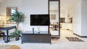 A modern living room with a flat-screen TV mounted on a dark wooden console, a large mirror, and a potted plant. - SuperHost - Deluxe Studio with Stunning Marina Views - JW Marriott Dubai Marina (Dubai)