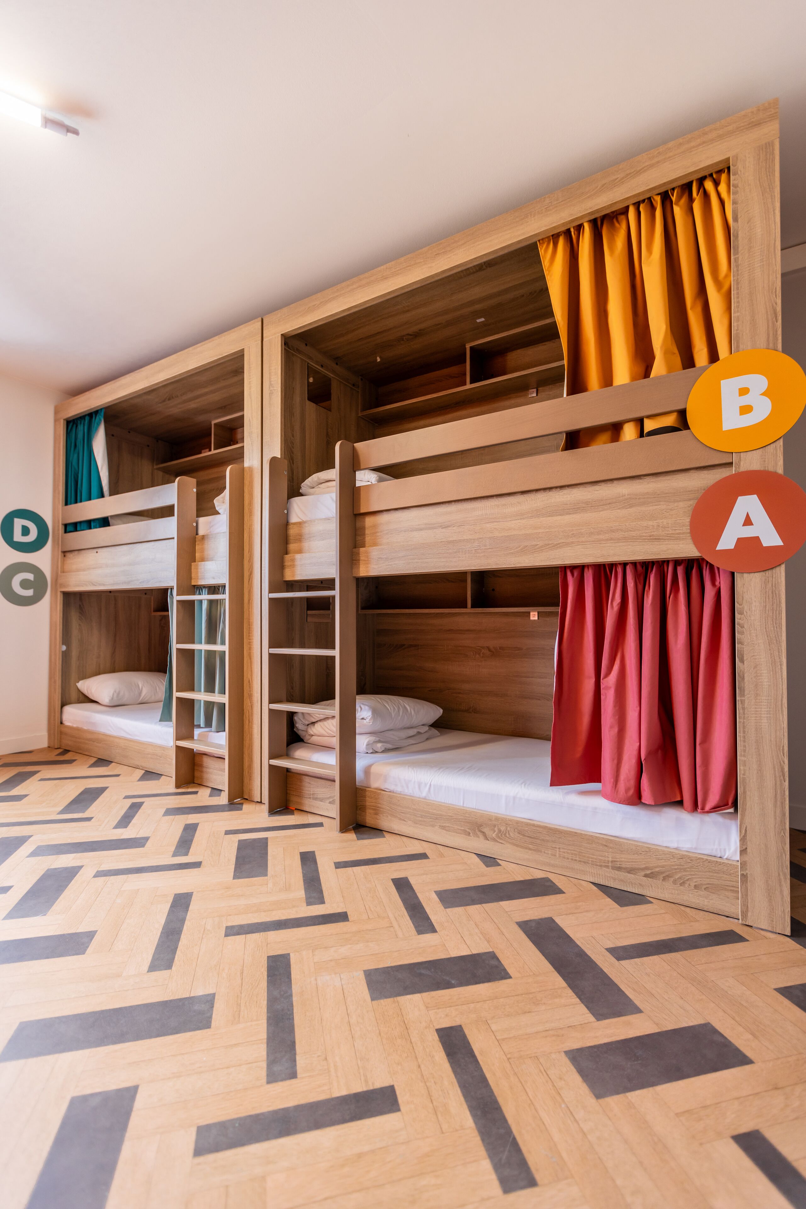 Dormitorio con literas, paredes de madera y suelo con estampado de espiga.
