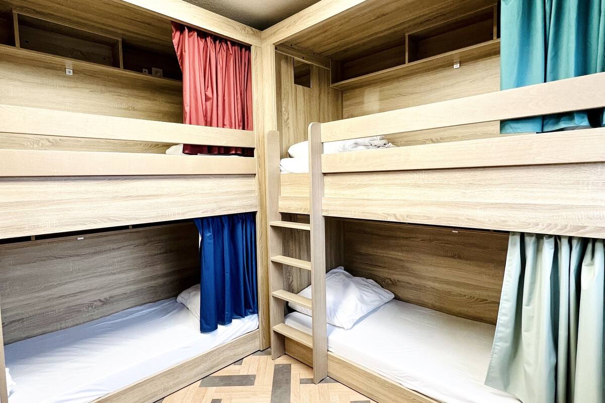 Een kamer met stapelbedden, houten wanden en een visgraatvloer.
