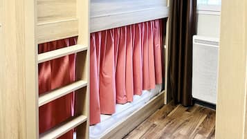Une chambre avec un lit superposé, des murs en bois, une fenêtre avec des rideaux et un radiateur.
