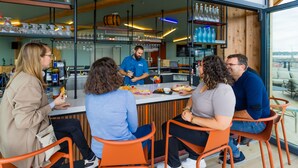Een groep mensen dineert in een modern restaurant, met een bar op de achtergrond.