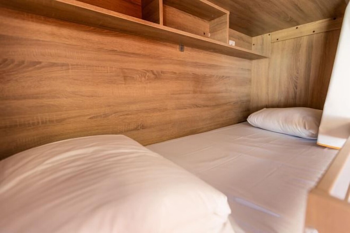 A compact wooden room with two single beds, each with white bedding.