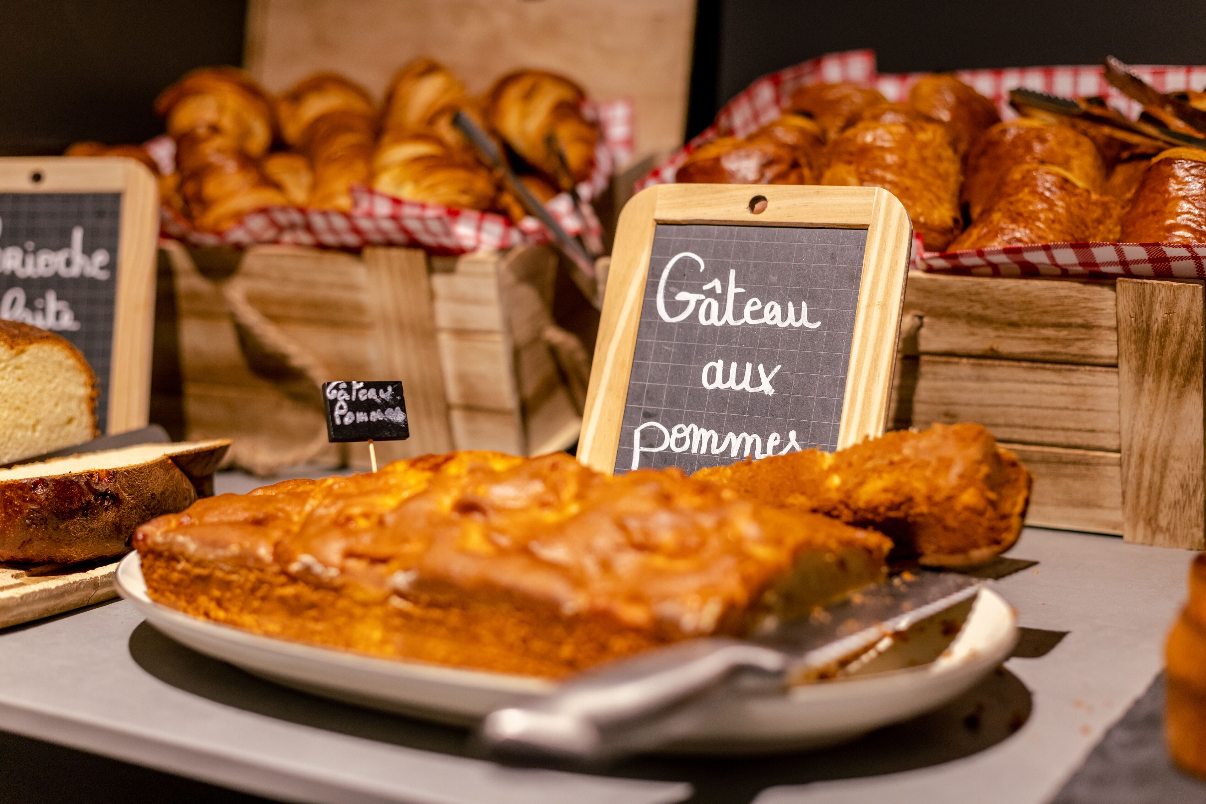 A display of baked goods including a cake, bread, and pastries, with signs indicating the types of food available.