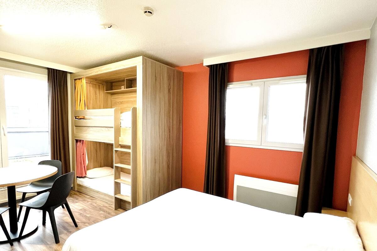 Een hotelkamer met een bed, een bureau en een stoel. Er is een raam met gordijnen.