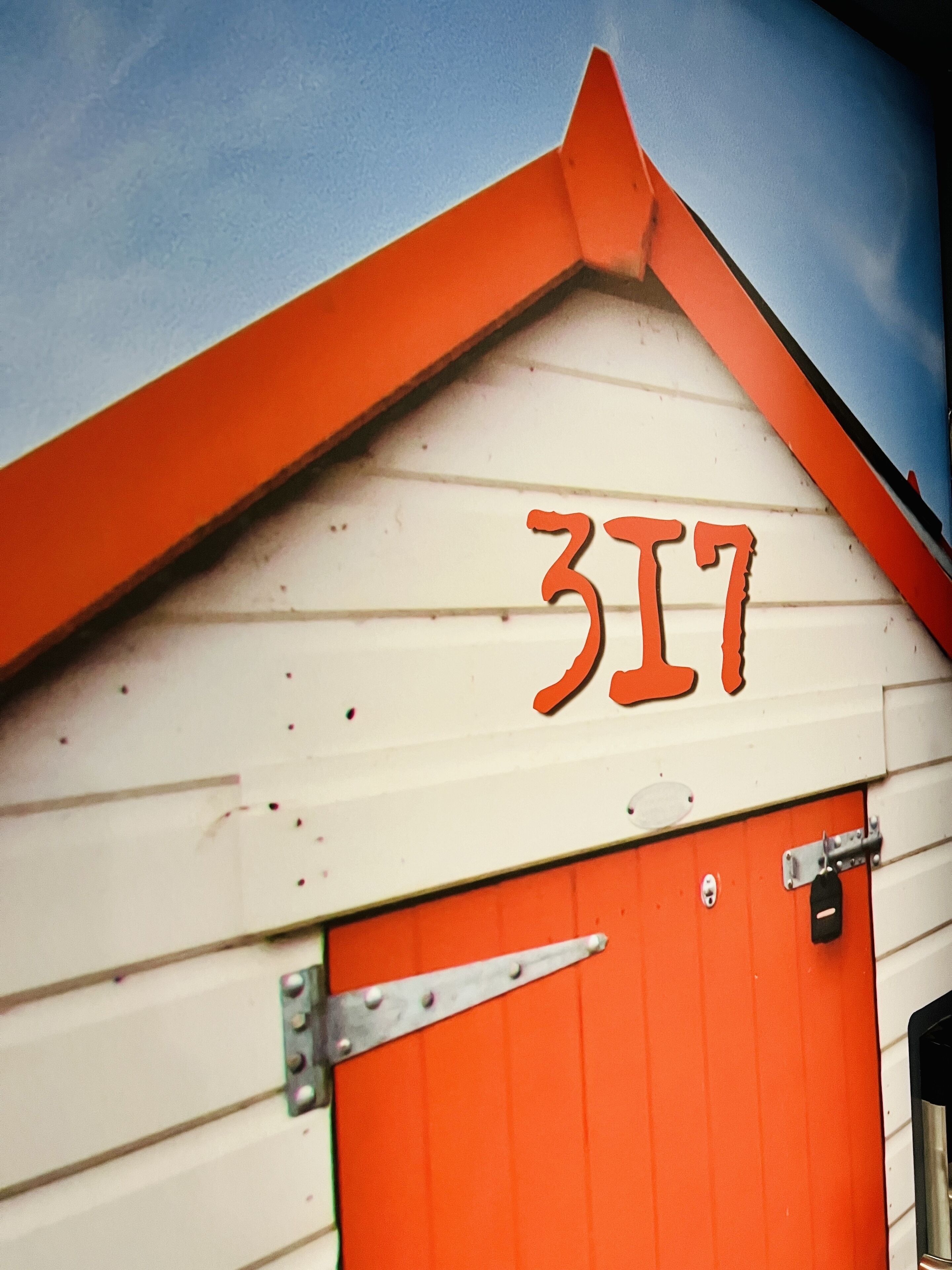 A building with a white exterior and an orange door. The number "317" is displayed on the building's facade.