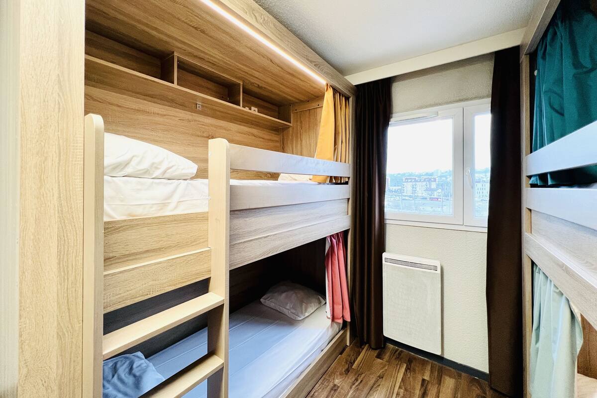 Een slaapkamer met stapelbedden, houten wanden en een raam met gordijnen.