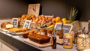 Een ontbijtbuffet met diverse gebakjes, fruit en toevoegingen.