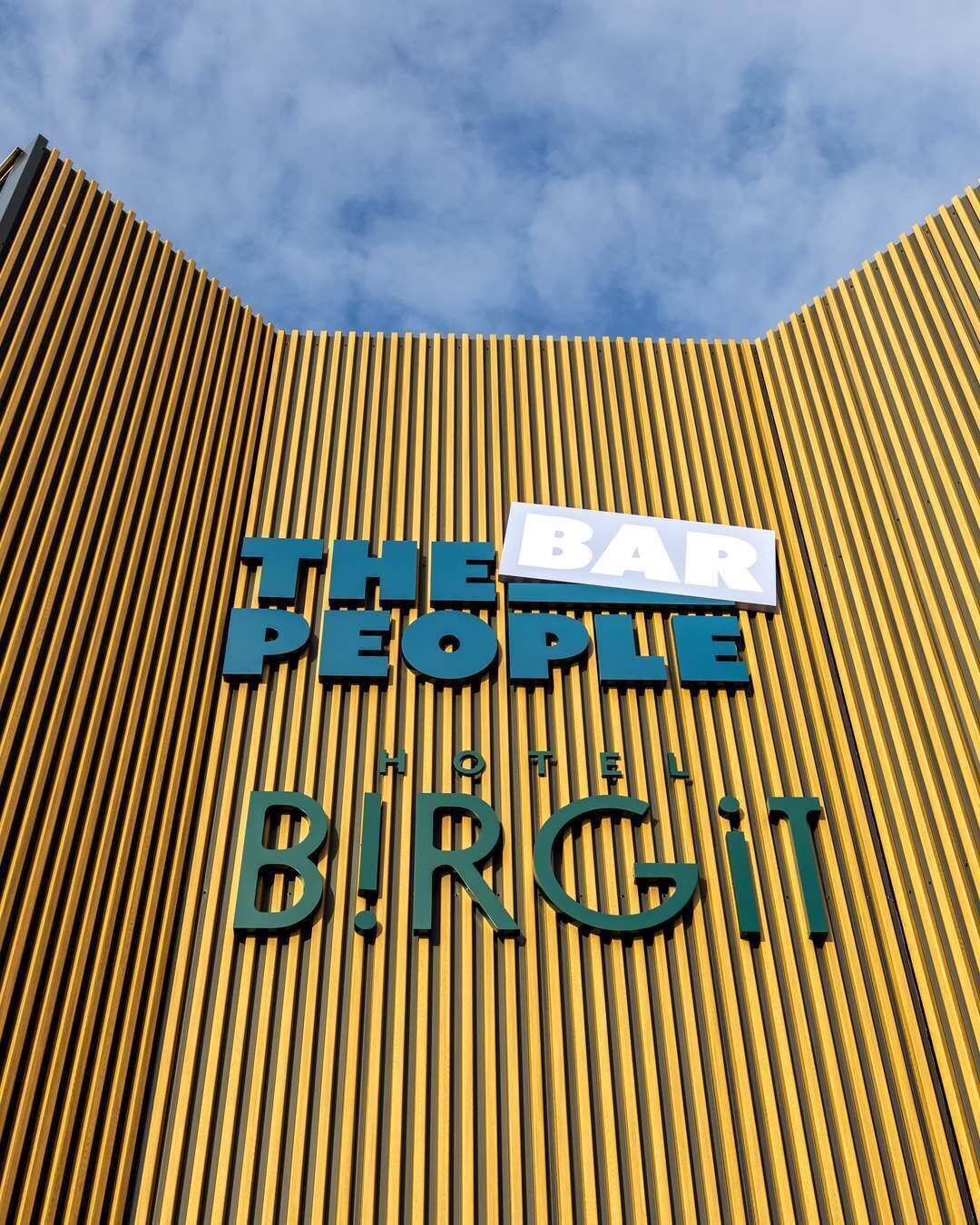 Fachada de edificio con listones verticales de madera y letreros que dicen 'The People Bar' y 'Birgit Hotel'.
