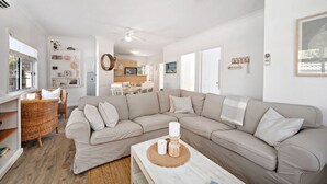 A modern living room with a beige sectional sofa, a wicker chair, and a wooden coffee table.