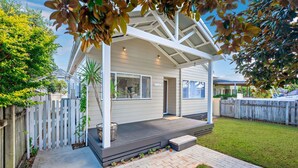 A single-story house with a covered porch, a fenced backyard, and a clear sky.