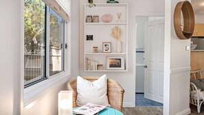 A cozy entryway with a wicker chair, a white pillow, and a bookshelf filled with books and decorative items.