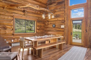 A wooden interior with a wooden table, chairs, and a bench.