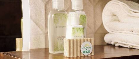 Two bottles of shampoo and a folded towel on a wooden surface with a textured wall in the background.