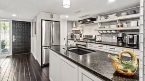 Una cocina moderna con electrodomésticos de acero inoxidable, armarios blancos y encimera de granito.