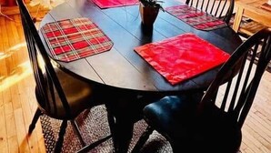 Un intérieur en bois comprenant une table à manger, des chaises, un sapin de Noël et une cheminée.