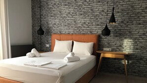 Et moderne hotelværelse med væg i murstensmønster, en træsenggavl og et natbord i træ.