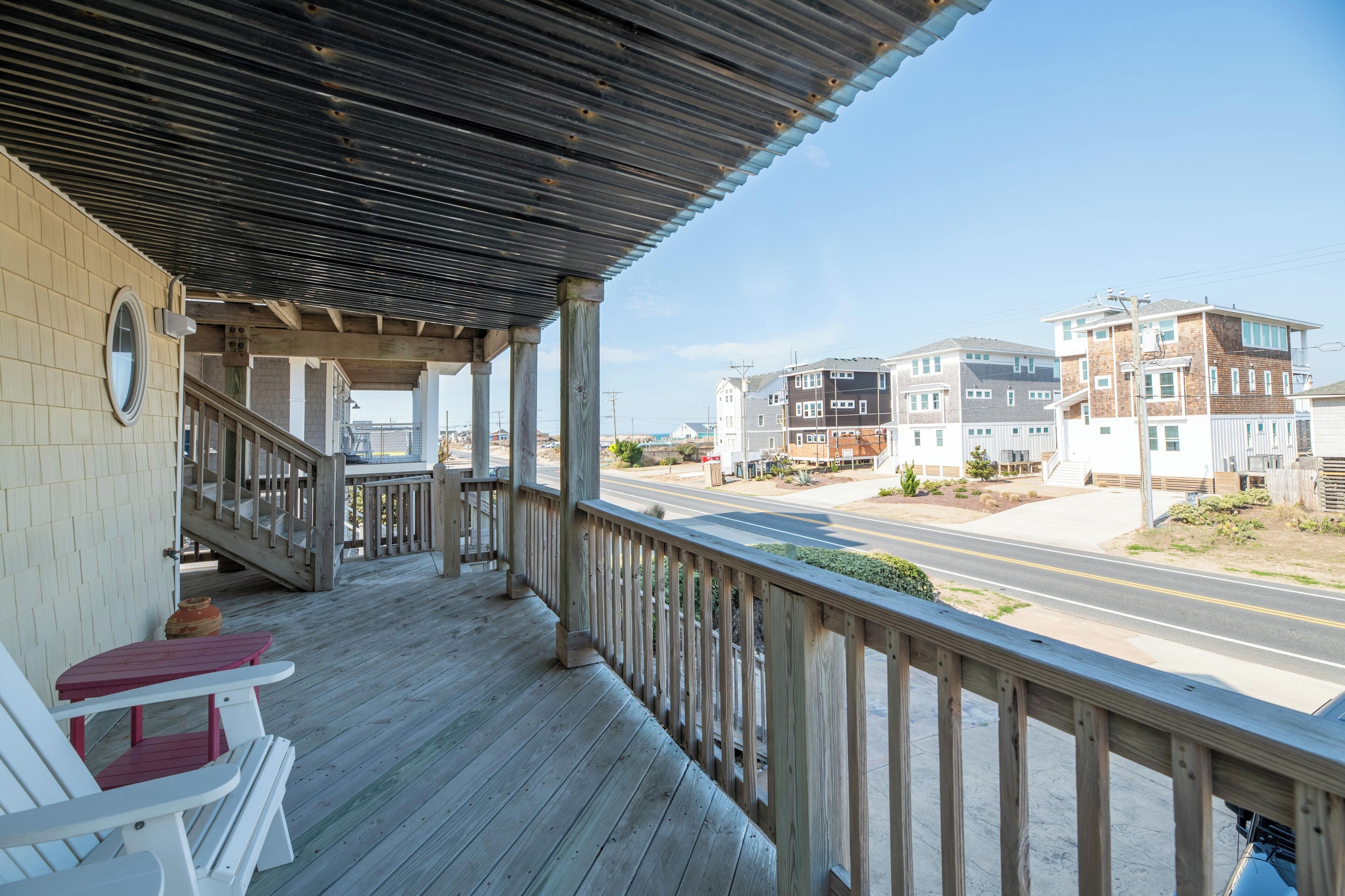 A wooden deck with a railing, a staircase, and a view of residential buildings.