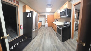 Una cocina con gabinetes de madera, electrodomésticos de acero inoxidable y un refrigerador negro.