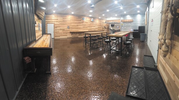 Un espacio interior amplio con piso pulido, bancos de madera y taburetes de bar.