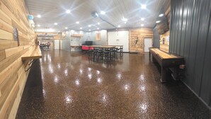 Un espacio interior amplio con piso pulido, paredes de madera y un largo banco a lo largo de un lado.
