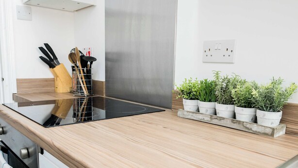 A kitchen with a wooden countertop, a stainless steel range hood, and a potted plant arrangement. - Sapphire Suite Moseley Birmingham STAE-Homes (Birmingham)