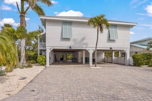 A two-story house with a covered porch and a paved driveway. - Sea Jay: Canal front with dock, heated pool, lanai w/outdoor kitchen (Anna Maria)