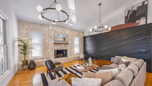 Uma sala de estar moderna com lareira de pedra, parede de madeira preta e um sofá grande.