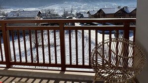 Een balkon met uitzicht op besneeuwde bergen en een heldere lucht.