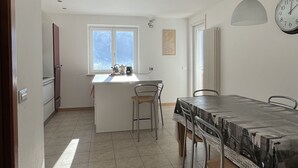 Een ruime keuken met een eethoek, een raam met uitzicht en een klok aan de muur.