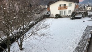 Een besneeerd landschap met een huis en bergen op de achtergrond.