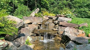 Une petite cascade dans un jardin, avec des rochers et de la verdure.