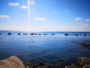 A coastal scene with clear water, rocks, and a distant horizon. - Suite Carducci (Gallipoli)